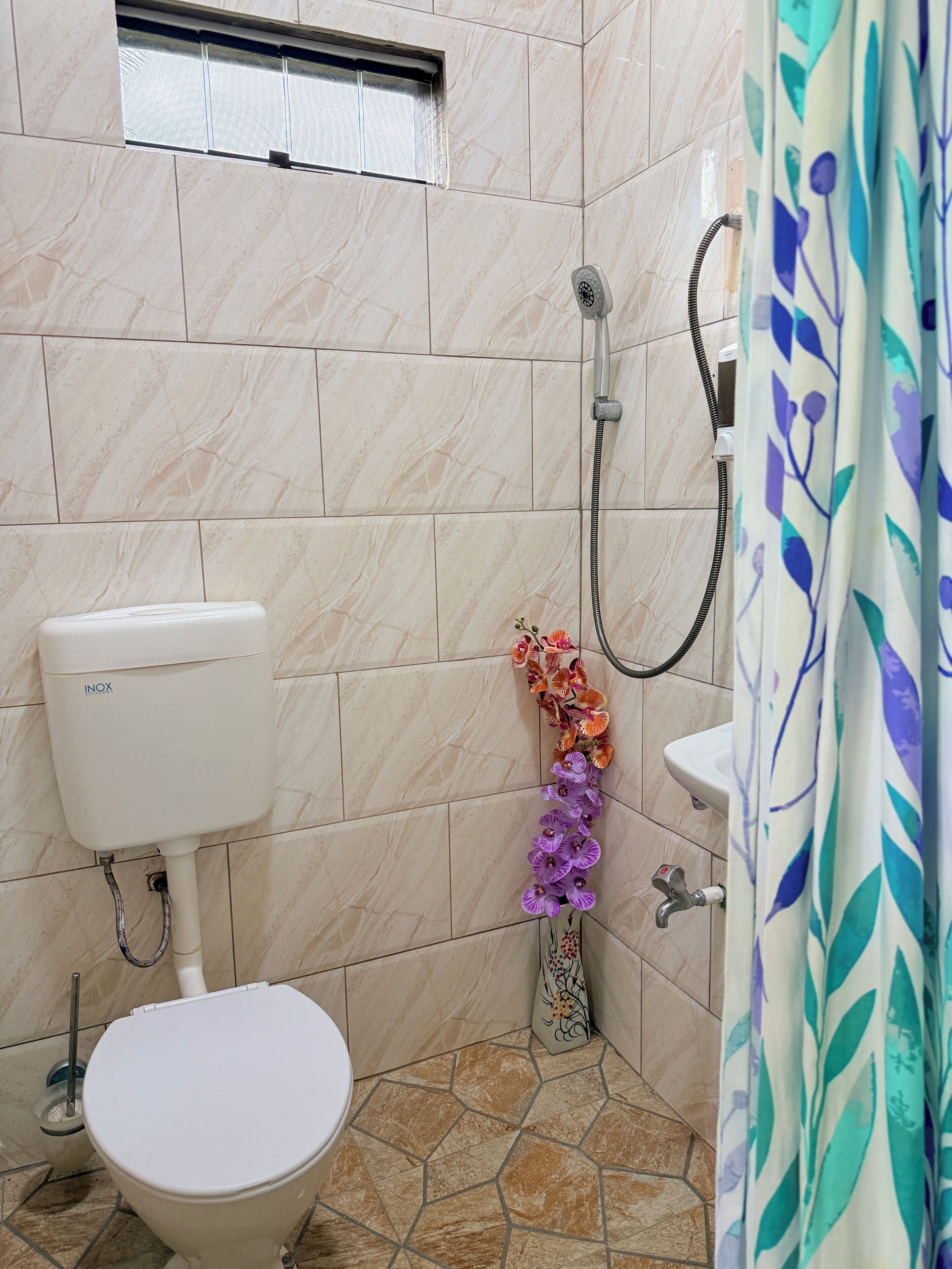 Ein Badezimmer mit Toilette, Dusche, Waschbecken und Fenster.