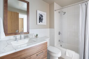 A modern bathroom with a marble sink, wooden vanity, a toilet, a shower with a glass door, and a framed picture on the wall. - Outpost: One Town Hill 204 - Base of Snow King Mtn (Jackson)