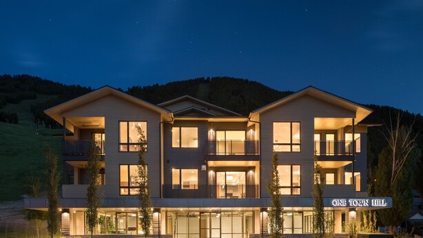 Un hôtel moderne à plusieurs étages, doté d’une entrée bien éclairée, de grandes fenêtres et d’une enseigne indiquant « ONE TOWN HILL ».