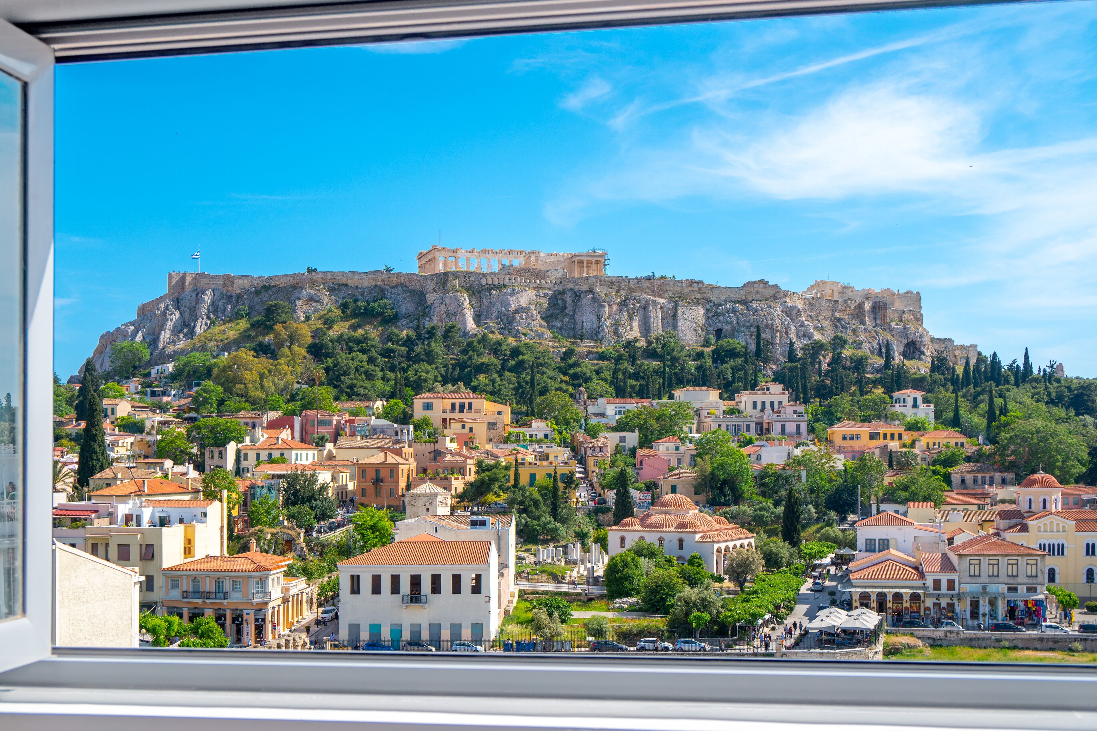 A view of a historic city with a prominent ancient castle on a hill, surrounded by residential buildings and greenery.