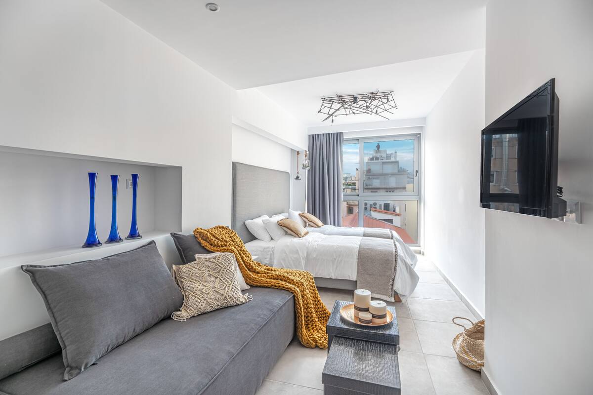 Una habitación moderna y bien iluminada, con sofá, cama y televisor.