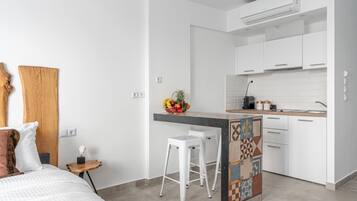 Una cocina moderna con armarios blancos, una isla central con taburetes y un frutero en la encimera.
