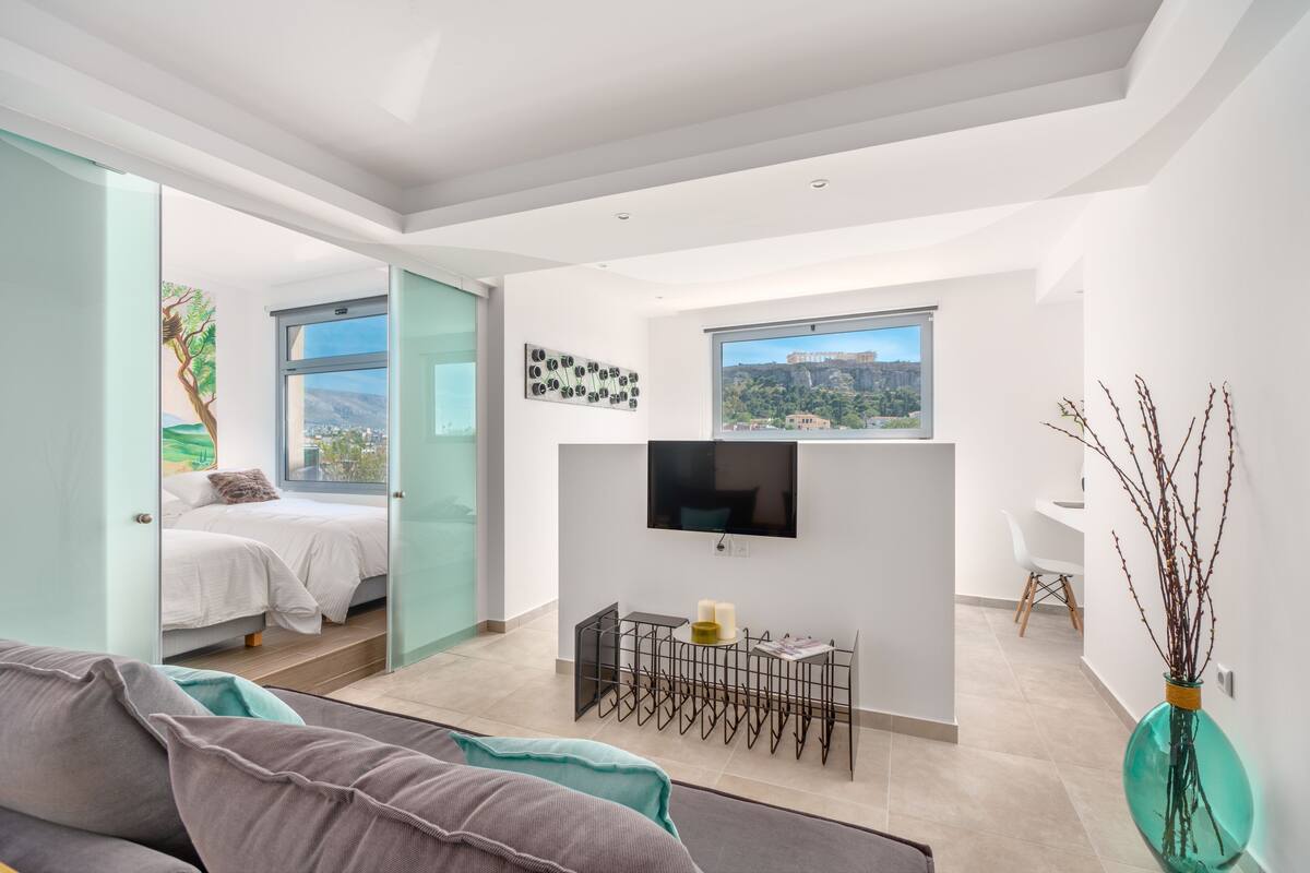 Un espacio habitable moderno y abierto con una cama, zona de comedor y televisor montado en la pared.
