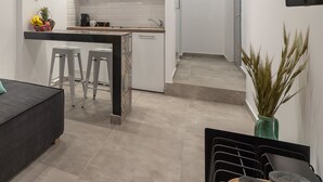 A modern kitchen with white cabinets, a central island, and a dining area with stools. - Mythos Luxury Suites (Athens)