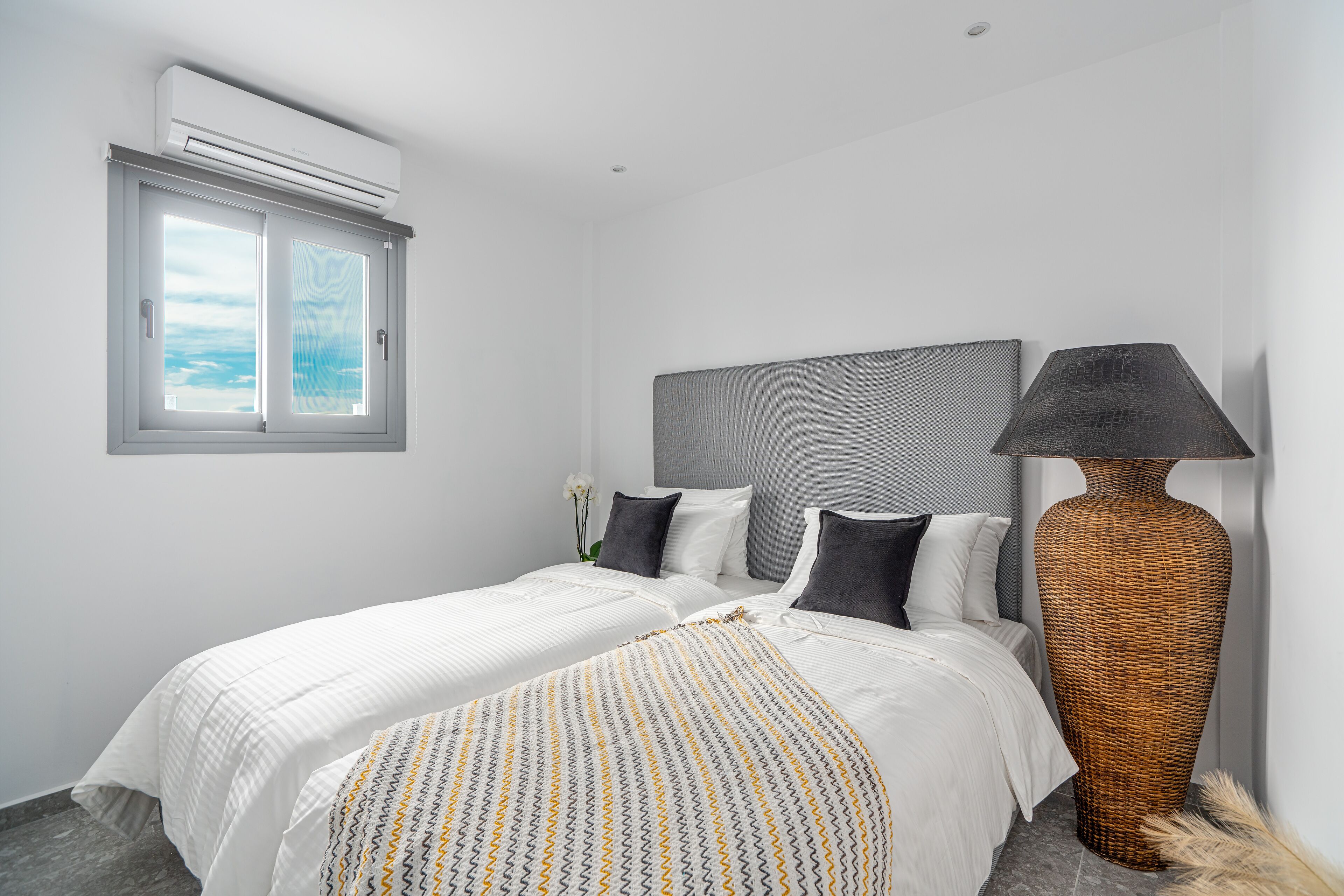 Un dormitorio con dos camas, una lámpara de pie en una jarra grande y una ventana con vistas.