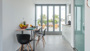 A modern kitchen with a dining area, large windows, and a view of the outdoors. - Mythos Luxury Suites (Athens)