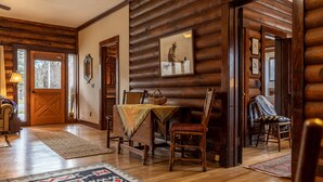 L’intérieur d’une cabane en rondins, avec un coin repas, des murs en bois et une cheminée.
