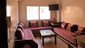 A living room with a sofa set, a coffee table, and a TV. - Tamraght apartment pool&wifi (Aourir)