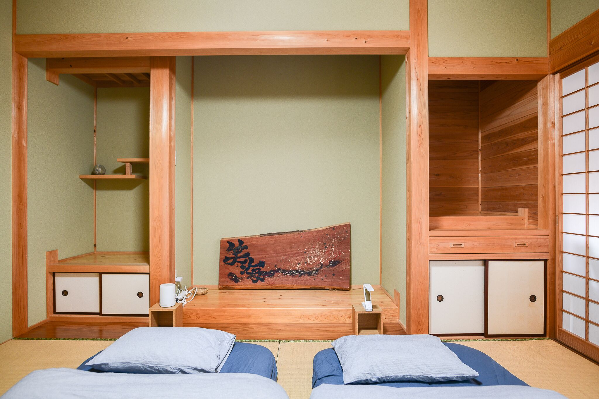 A traditional Japanese-style room with tatami flooring, a low wooden bed, and sliding doors.