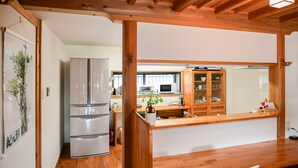 A kitchen with wooden beams, a refrigerator, a microwave, and a wooden cabinet. - Yakushima South Coast House (Yakushima)