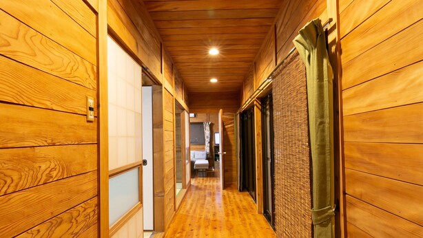 Un couloir en bois, doté d’un plancher poli, de murs en bois et d’une source de lumière vive à l’extrémité.