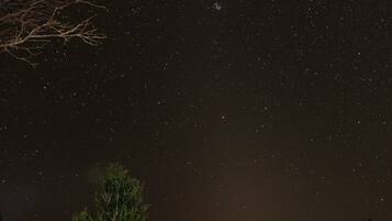 Two people sitting on a wooden deck under a starry night sky.