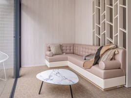 A modern living room with a beige sectional sofa, a marble coffee table, and a geometric-patterned rug.