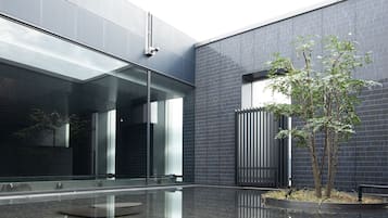 A modern building with large glass windows, a reflective floor, and a small tree in a planter.