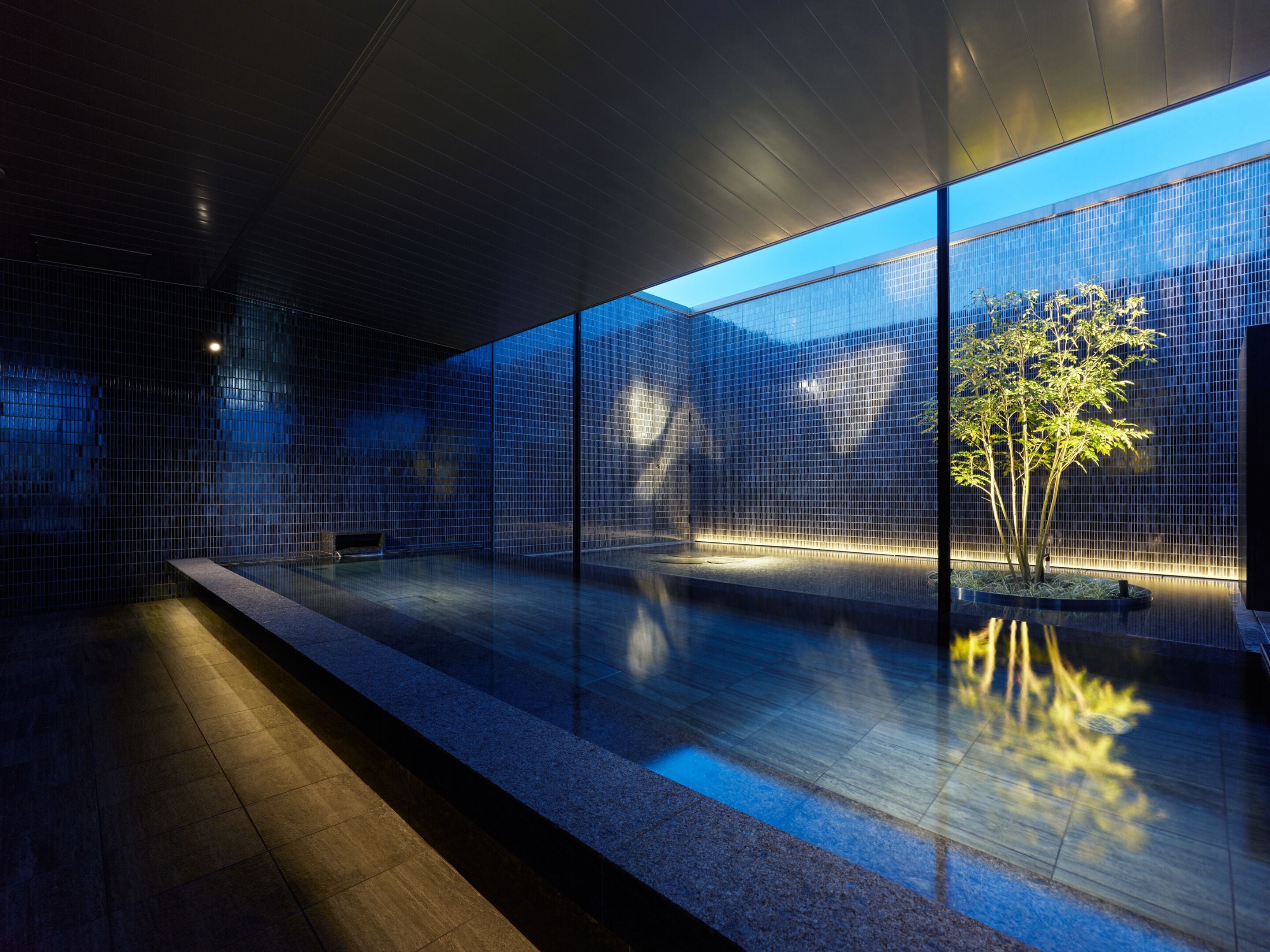 Um interior moderno com piso refletivo, um banco e uma divisória de vidro.