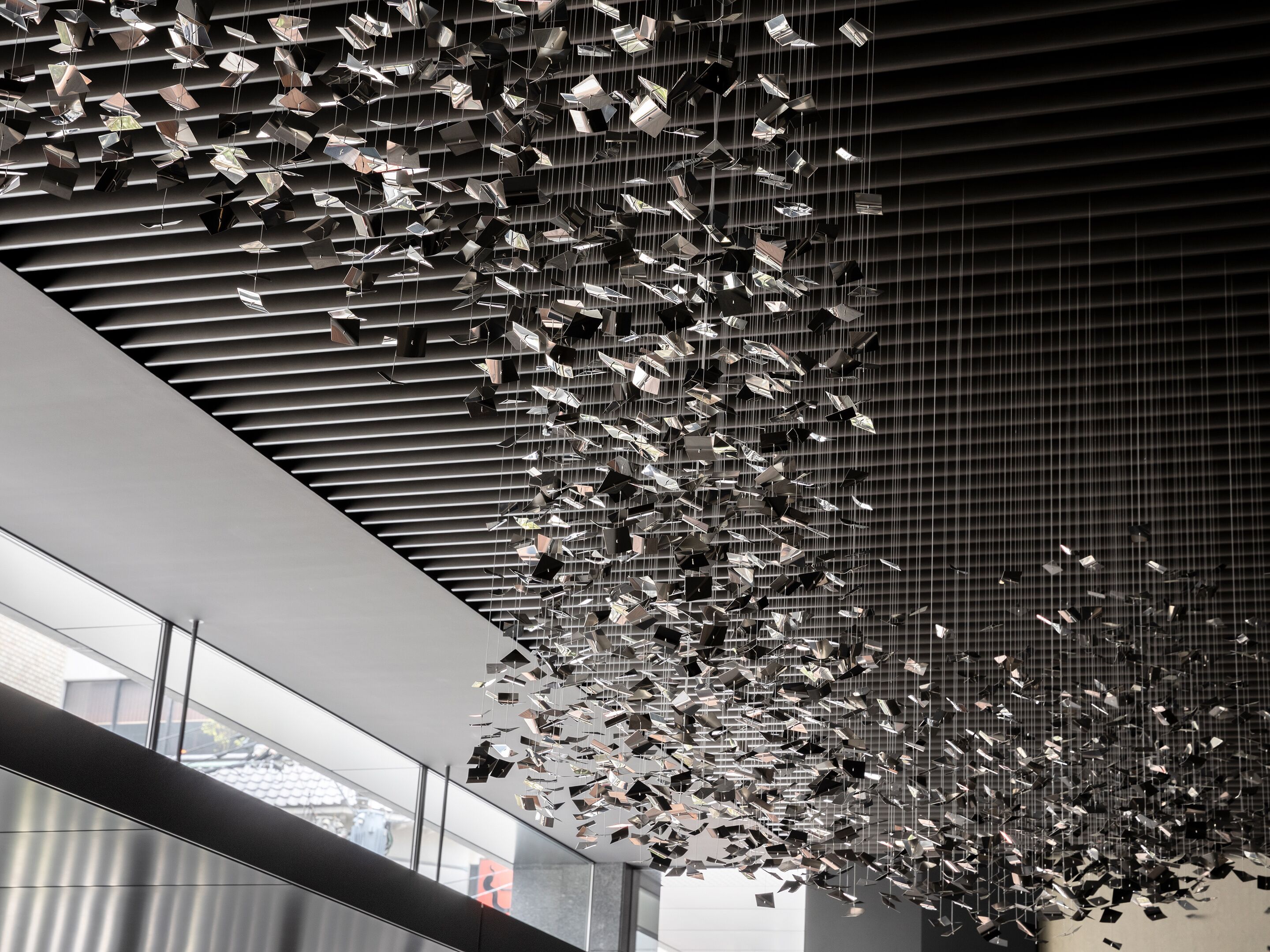 A modern interior with a ceiling installation of reflective metallic elements.