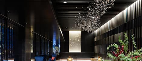 A modern lobby with seating, a decorative ceiling, and a view of the outside.