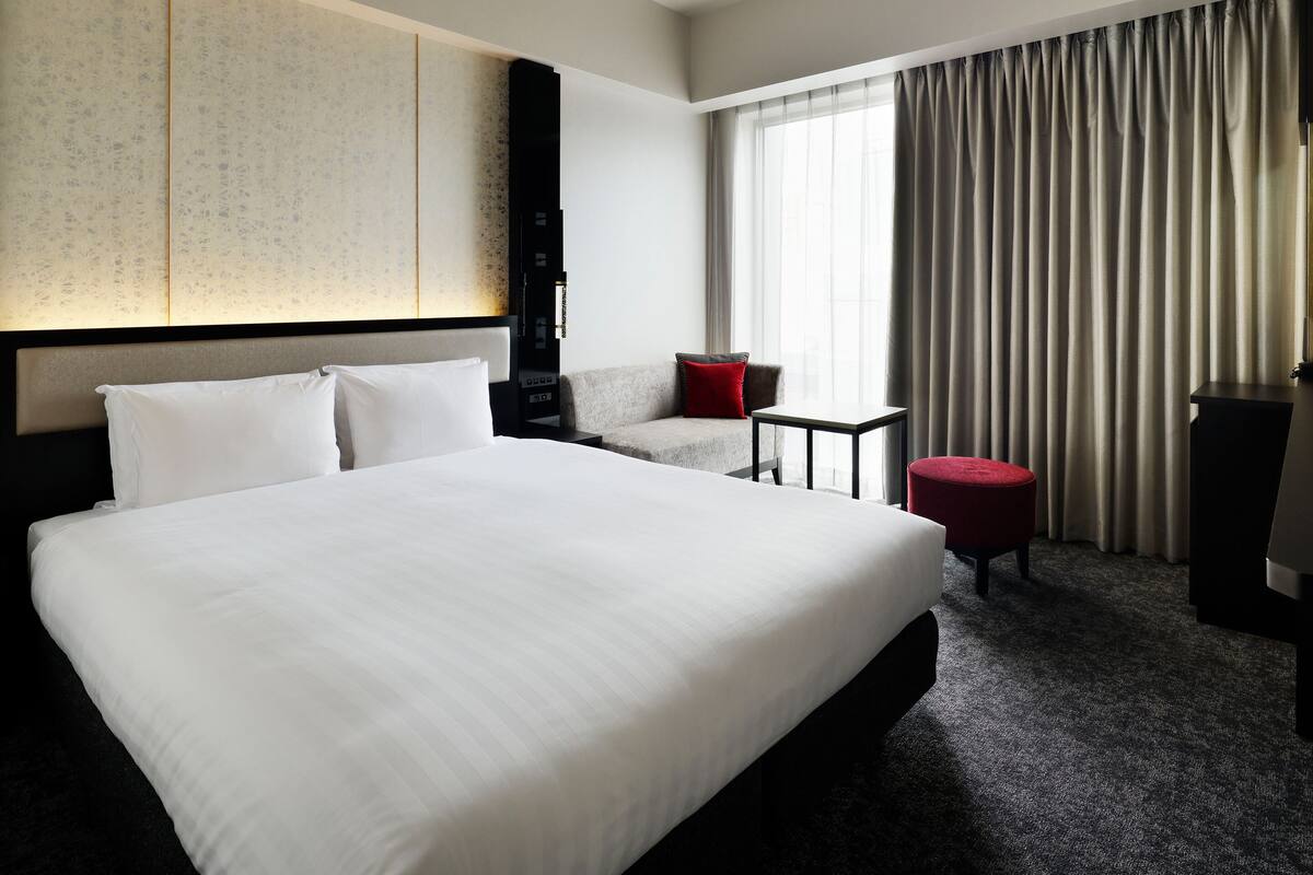 Une chambre d’hôtel dotée d’un grand lit, d’un coin salon et offrant une vue sur l’extérieur.