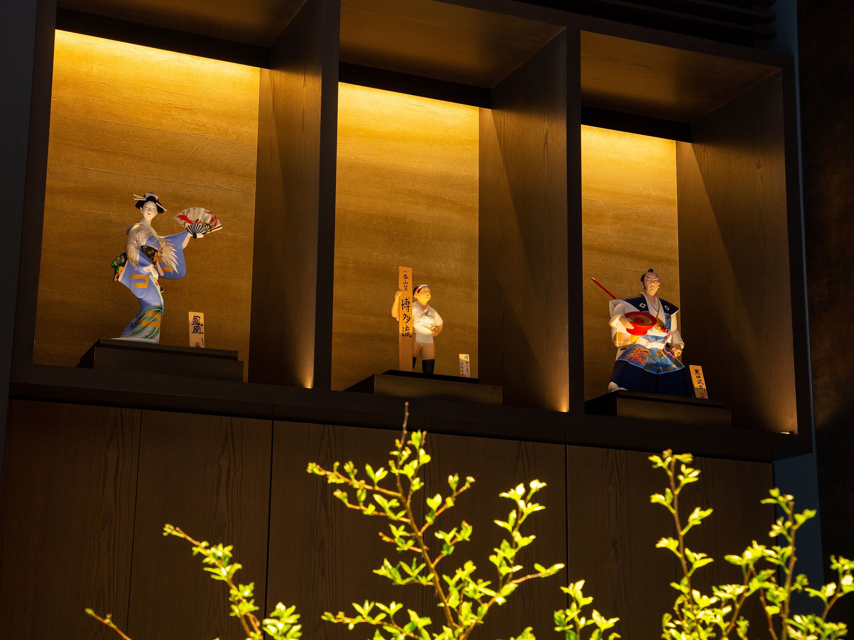 A display of traditional Japanese figures on shelves with illuminated backgrounds.