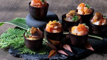 A series of dishes arranged on a dark slate serving board, accompanied by green foliage and decorative leaves.