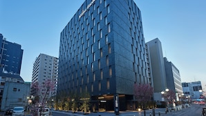 A modern hotel with a prominent "Mitsui Garden Hotel" sign, surrounded by other buildings and a clear sky. - Mitsui Garden Hotel Fukuoka Nakasu (Fukuoka)