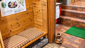 A wooden cabin interior with a bench, a poster on the wall, and a small altar.