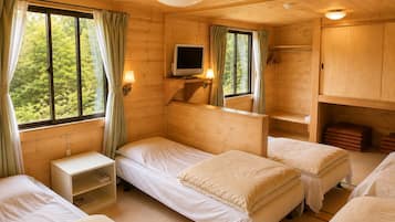 Une chambre de style cabane avec trois lits, une télévision et une fenêtre avec des rideaux.