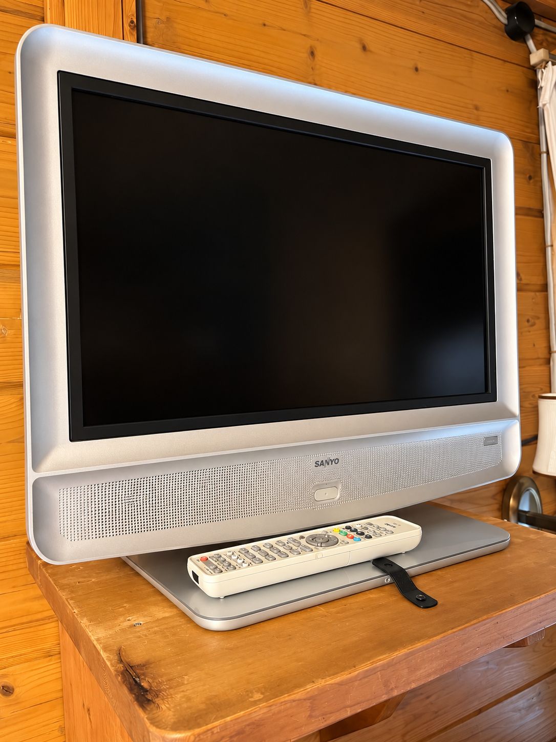 Ein Flachbildfernseher mit Fernbedienung auf einem Holztisch.