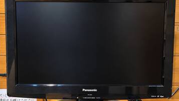 Een Panasonic tv op een houten standaard, met een afstandsbediening ernaast.