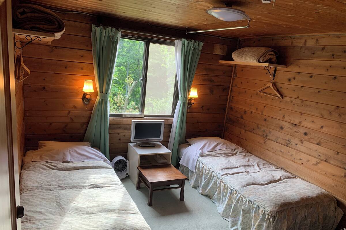 A cabin room with two beds, a TV, and a small table.