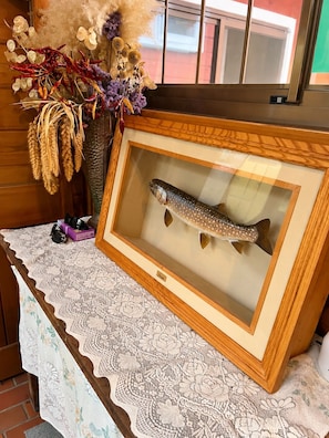 A framed fish specimen on a table with a lace tablecloth, surrounded by dried plants and flowers. - Pension Poka Poka (Katashina)
