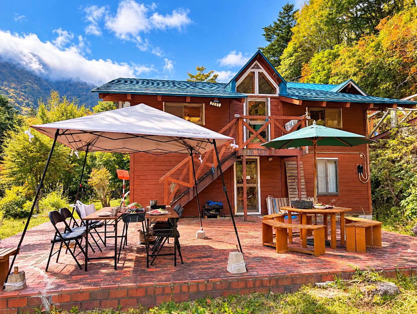 A wooden cabin with a covered patio, outdoor seating, and a staircase leading to an upper level.