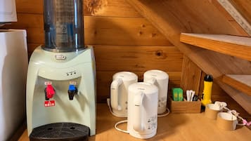 Un sauna équipé d’un panneau de commande, d’un chauffe-eau et de plusieurs appareils de chauffage pour sauna blancs, le tout posé sur une table en bois.