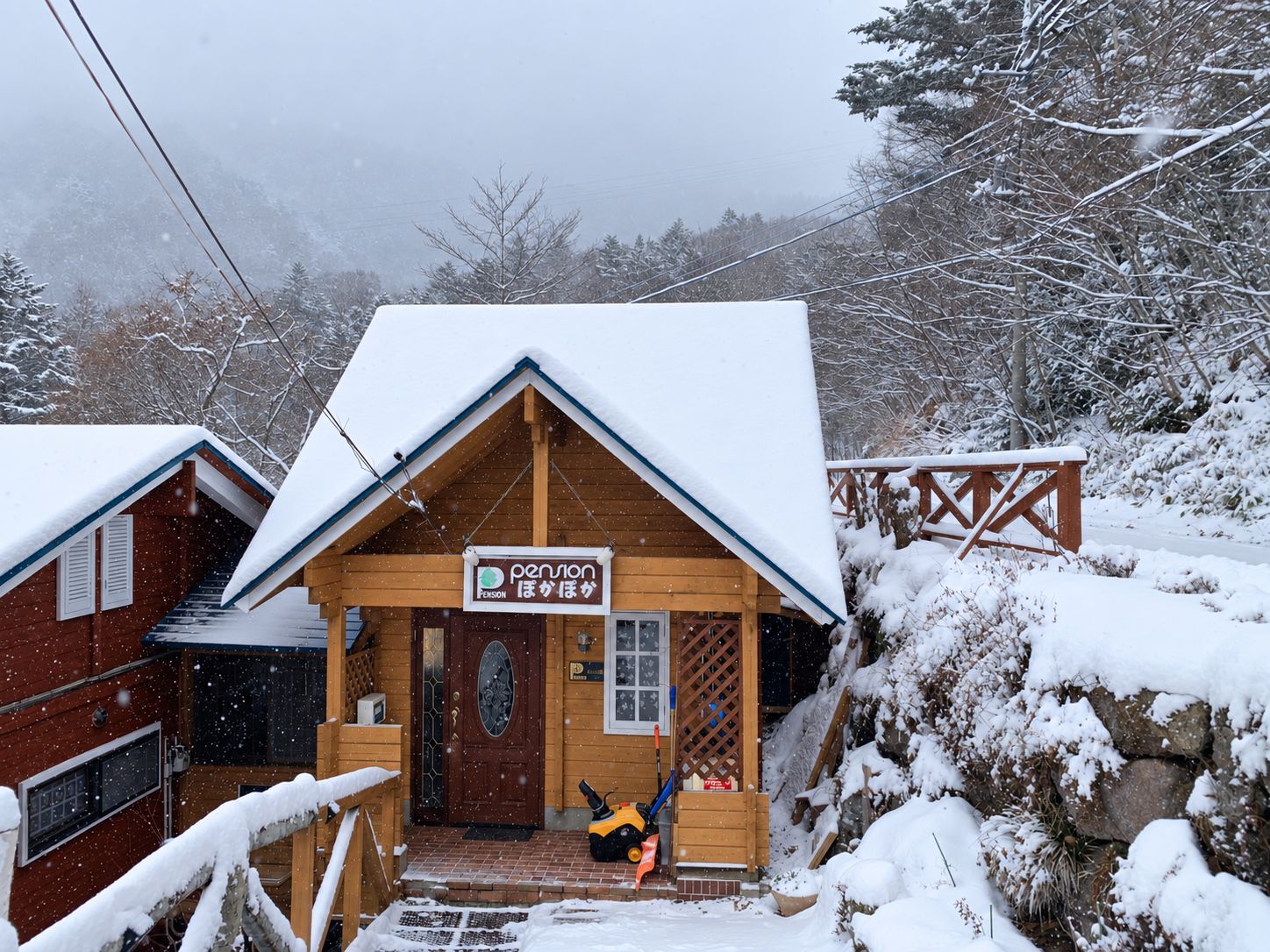 A wooden cabin with a snow-covered roof and a sign indicating it is a pension.