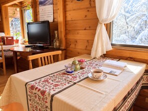 A cozy room with a wooden interior, a table set with a cup of tea, a book, and a teapot. - Pension Poka Poka (Katashina)