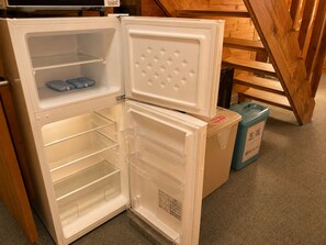 An open refrigerator with multiple shelves and a freezer compartment. - Pension Poka Poka (Katashina)