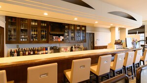 A bar area with wooden cabinets, a long counter, and several chairs. - Tabist Miya Yokkaichi Suizawa (Yokkaichi)