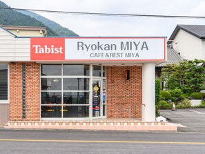Ryokan MIYA, un café y casa de descanso con un estilo arquitectónico japonés tradicional, presenta una fachada de ladrillo y grandes ventanales.