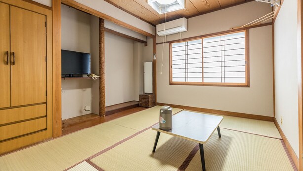 A traditional Japanese room with tatami flooring, a low table, a heater, and a sliding door. - Tabist Miya Yokkaichi Suizawa (Yokkaichi)