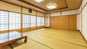 A traditional Japanese room with tatami flooring, sliding doors, and a wooden table. - Tabist Miya Yokkaichi Suizawa (Yokkaichi)