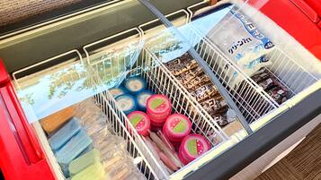 Un carrito de compras lleno de diversos productos envasados, incluyendo frascos y recipientes, en un ambiente de tienda.
