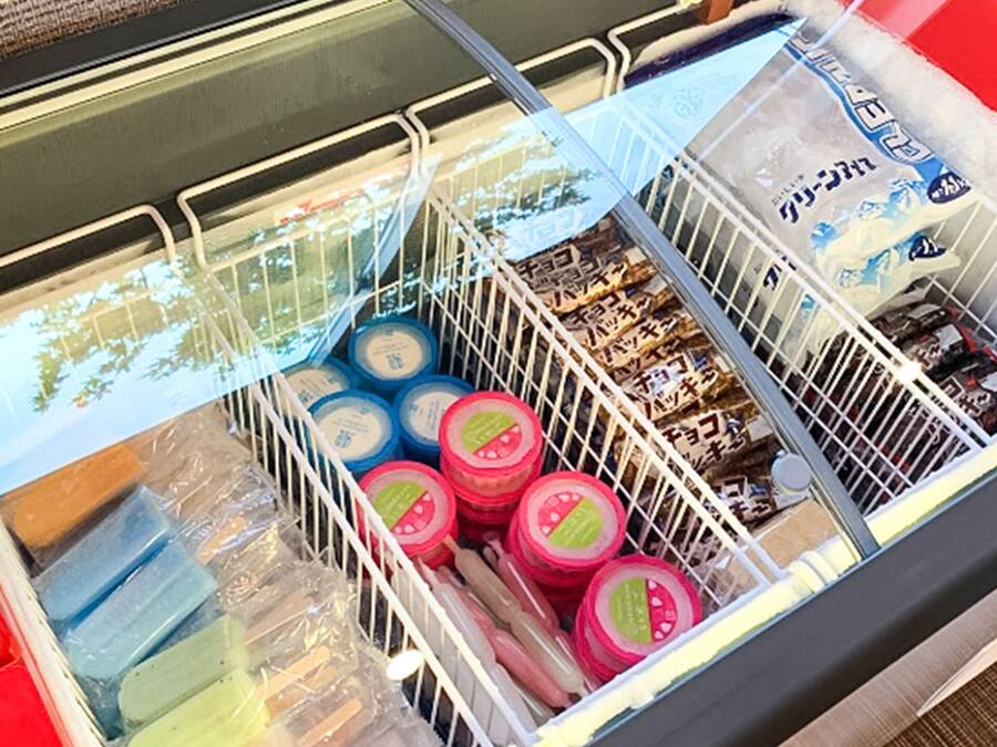 Un carrito de compras lleno de diversos productos envasados, incluyendo frascos y recipientes, en un ambiente de tienda.