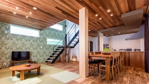Un espacio habitable moderno con piso de madera, televisor, comedor y cocina.