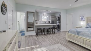 Quarto moderno com cama grande, escrivaninha embutida com bancos, máquina de lavar e ventilador de teto.