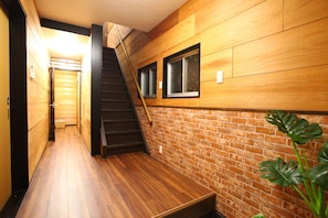 Staircase leads to a cozy space with a brick-patterned wall and wooden paneling.