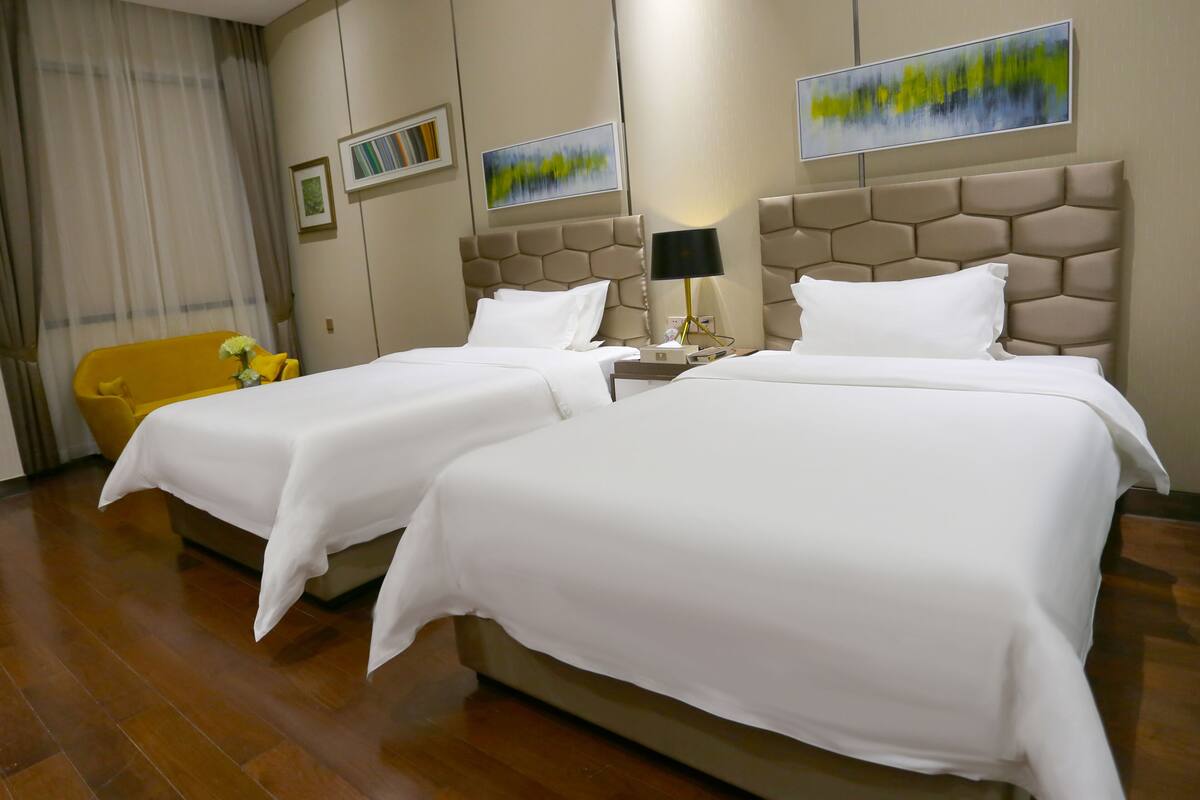 A hotel room with two beds, a sofa, and artwork on the walls.