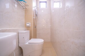 A bathroom with a toilet, a shower, and a window.