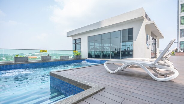 A rooftop pool area with a modern pool, lounge chairs, and a building with large windows. - OYO Home 89458 Amazing 2br D'summit (Johor Bahru)