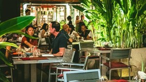 An indoor dining area with tables and chairs, surrounded by large green plants. - Kata Gardens 2br Holiday Apartment 8A (Karon)
