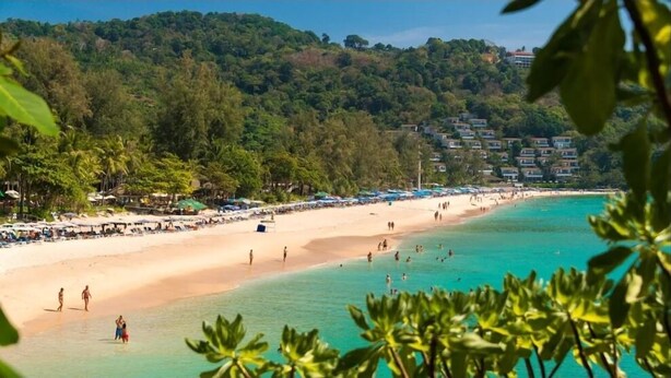 A beach with clear turquoise water, a sandy shore, and a backdrop of dense green hills. - Kata Gardens 2br Holiday Apartment 8A (Karon)